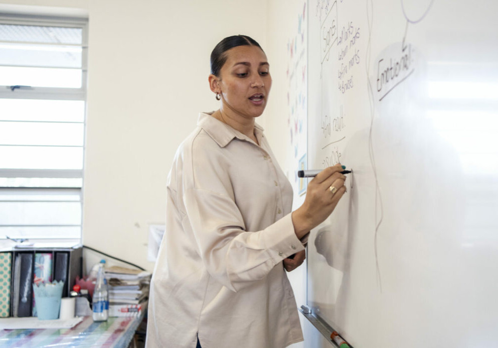 Female teacher writing on a whiteboard while teaching in classroom