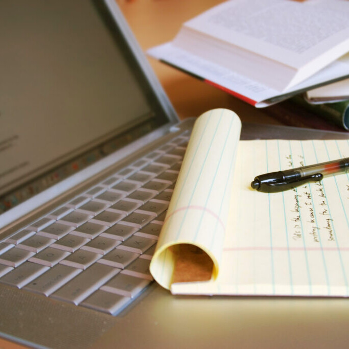 Laptop computer with books, pen and yellow legal pad